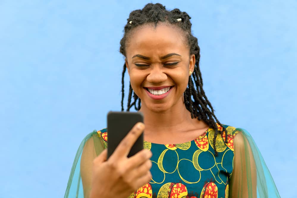 Young African girl with researching rosewater leaves in her iPhone 10