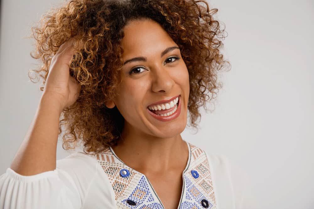 Happy African American lady after using a blow dryer to make her curls fluffy