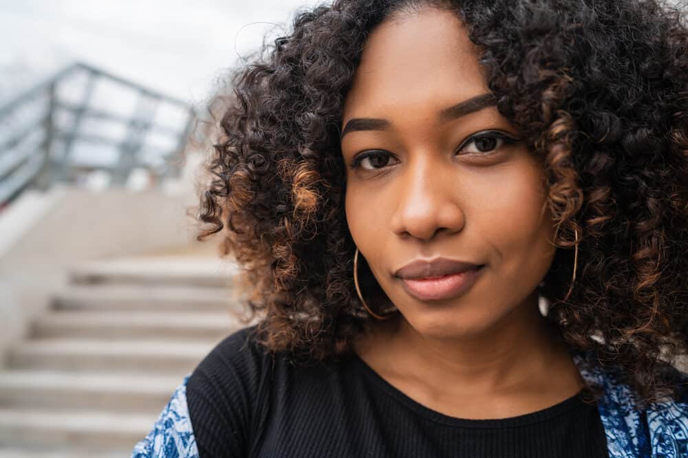 African American female with curly low porosity hair wearing gold earrings