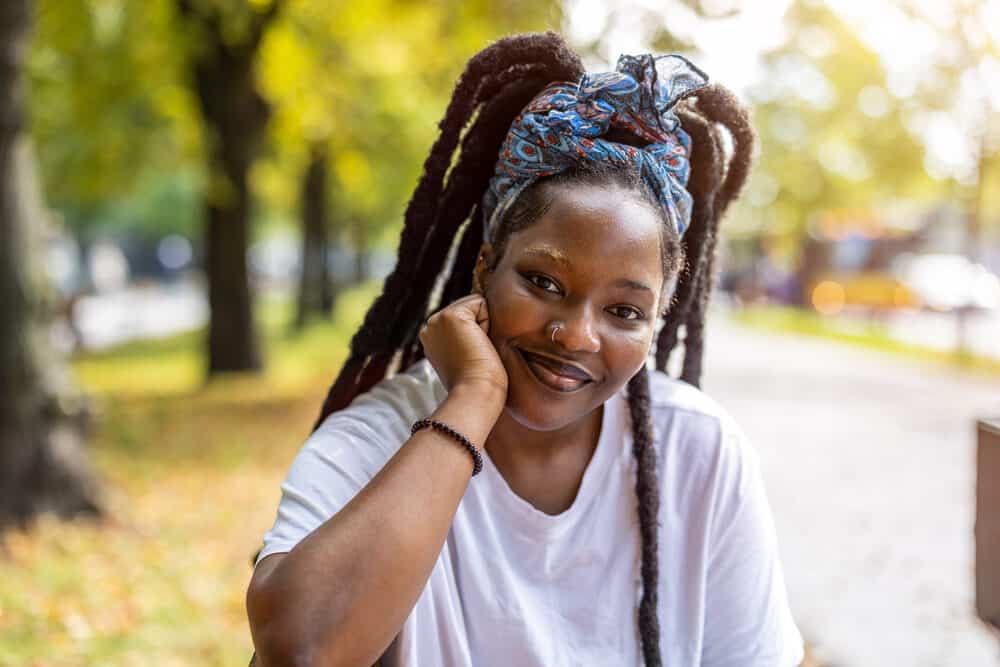 Black woman with a 4C hair texture wearing healthy wick dreadlocks with an infamous upright habit