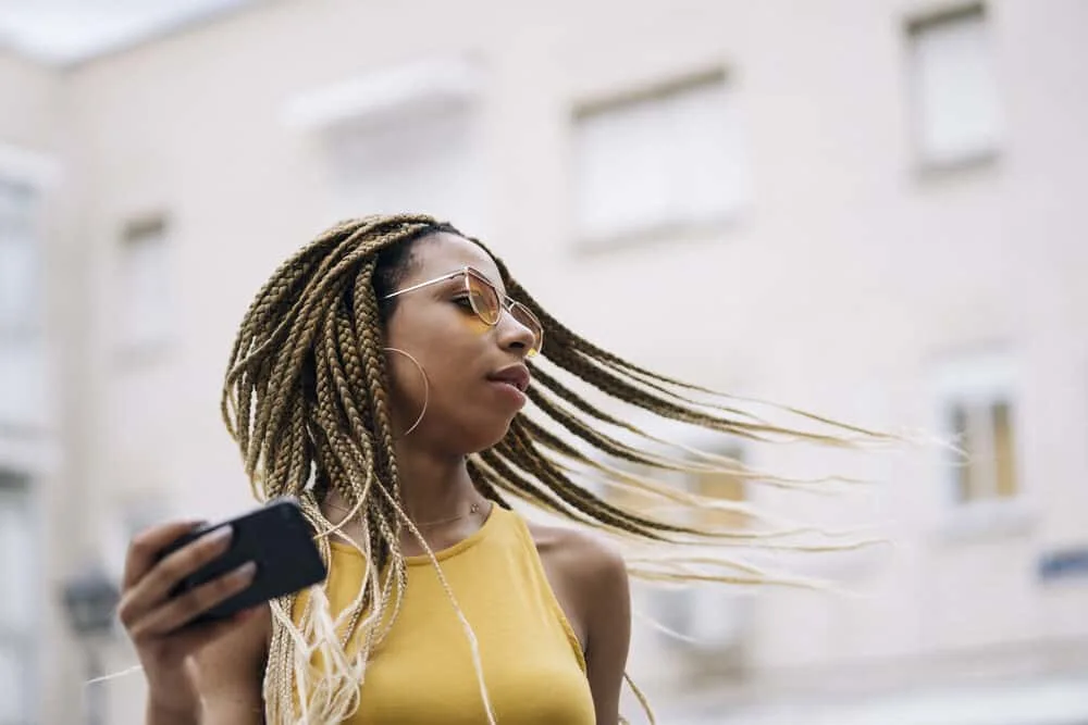 How To Fix Frizzy Braids and Keep Braids From Frizzing Up 2 Latin woman with healthy hair under blonde mini braids using an iPhone outside