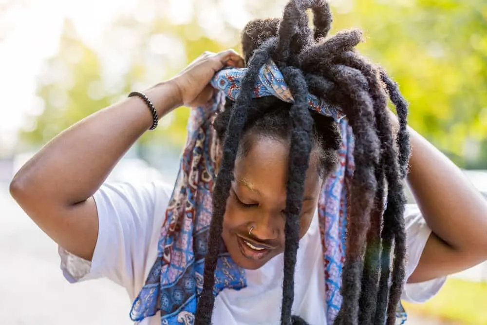 African American female with wick locs that were created by tying existing dreadlocs together to develop wicks