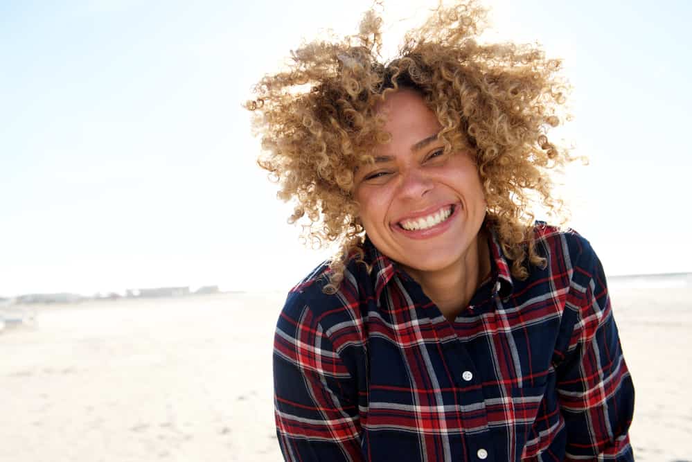 African American lady with freshly toned hair wearing a flannel shirt on a sunny day