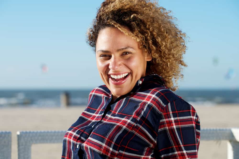 Young black lady outside at the beach with bleached hair color and brassy hair strands