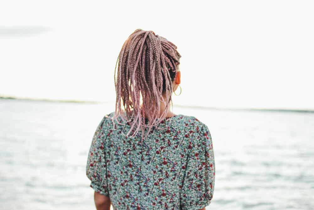 Cute white girl standing near the beach wearing braids on her own hair 