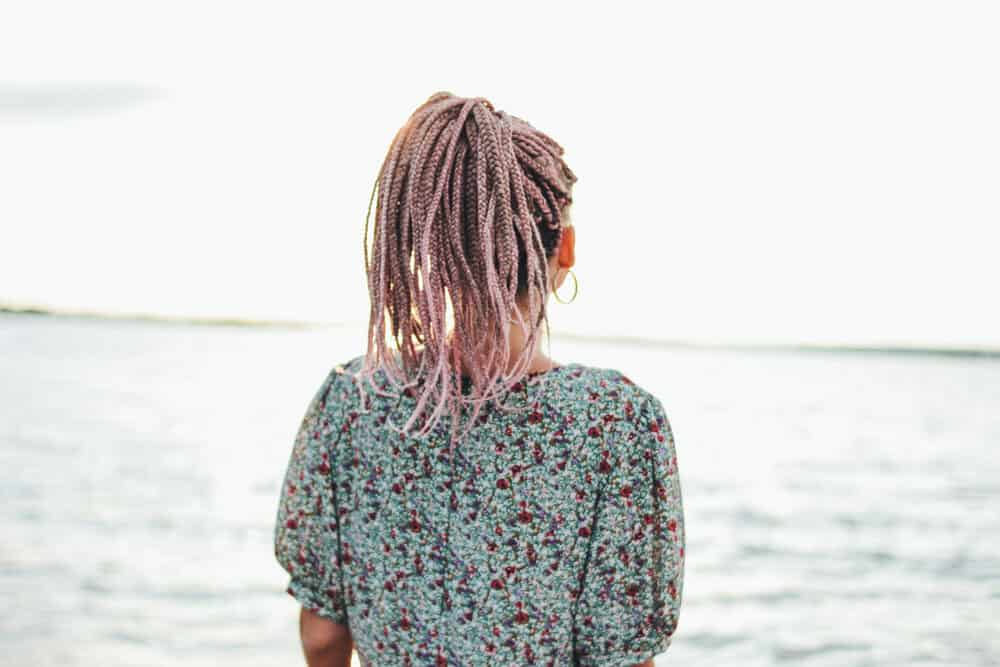 Cute white girl standing near the beach wearing braids on her own hair