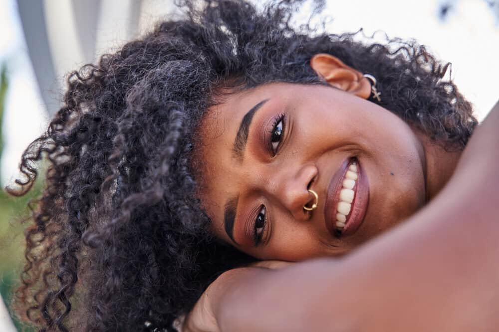 Latina with freshly washed curly hair wearing a nose ring and dark red lipstick