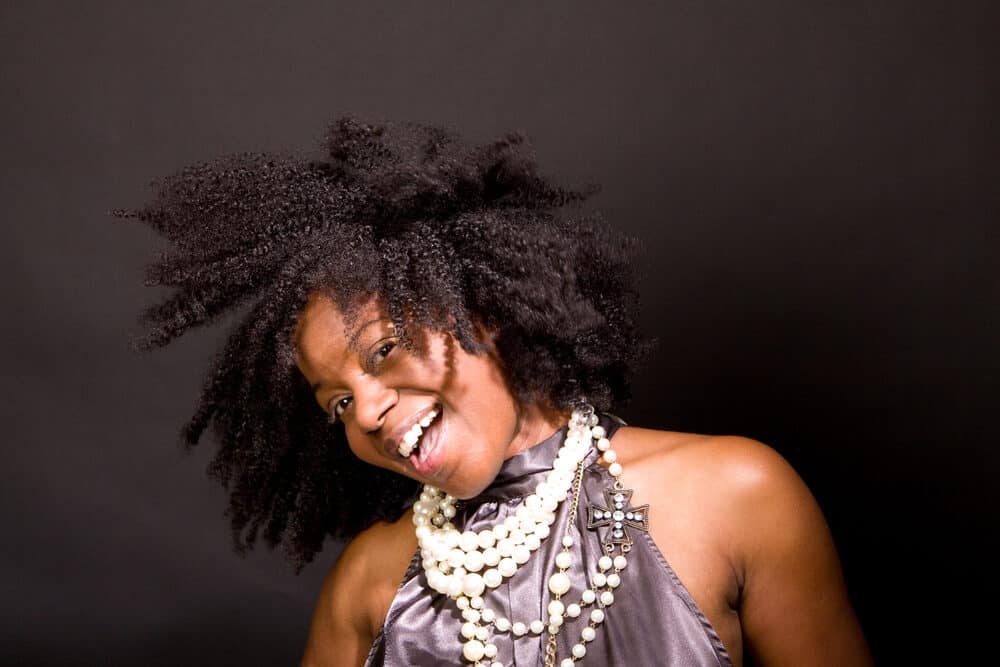 Black lady with kinky hair knots laughing as she flips from side-to-side