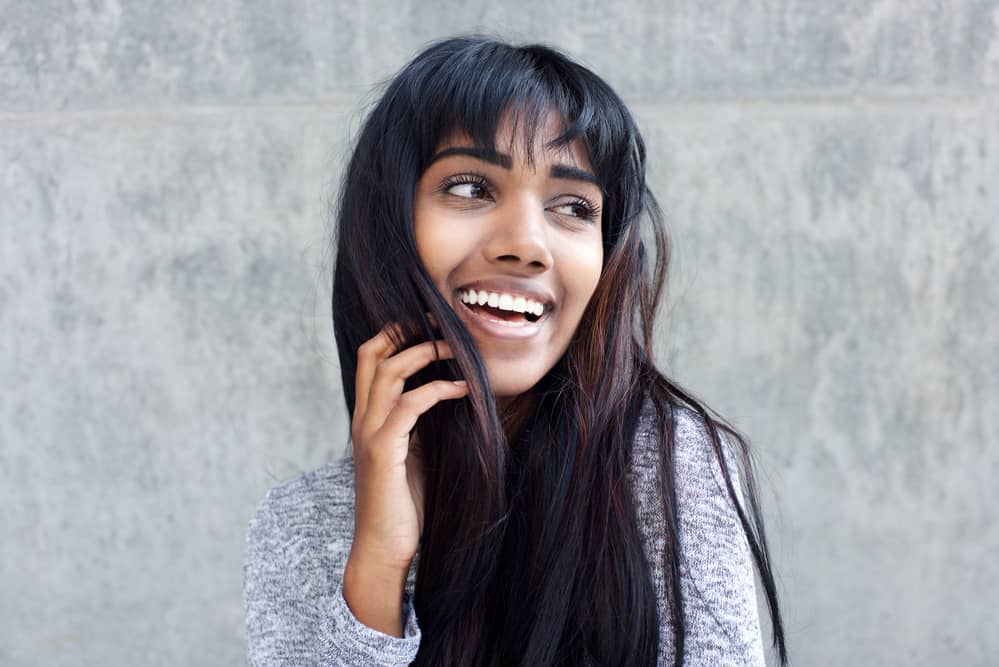 Young Indian woman wearing brown and black hair extension clip-ins with a gray sweater