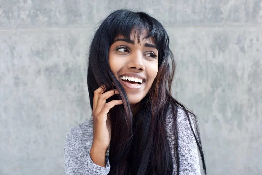 Are Hair Extensions Haram or Halal? Human vs Synthetic Hair? 1 Young Indian woman wearing brown and black hair extension clip-ins with a gray sweater