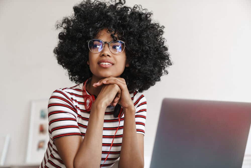 African American student with long hair searching for hair modeling jobs on her Macbook