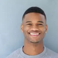 With his thick, coarse hair strands, this handsome young black man expertly used a cordless trimmer with self-sharpening blades and an Andis T-outliner to achieve a precise and even trim, showcasing his attention to detail and skill with hair styling tools.