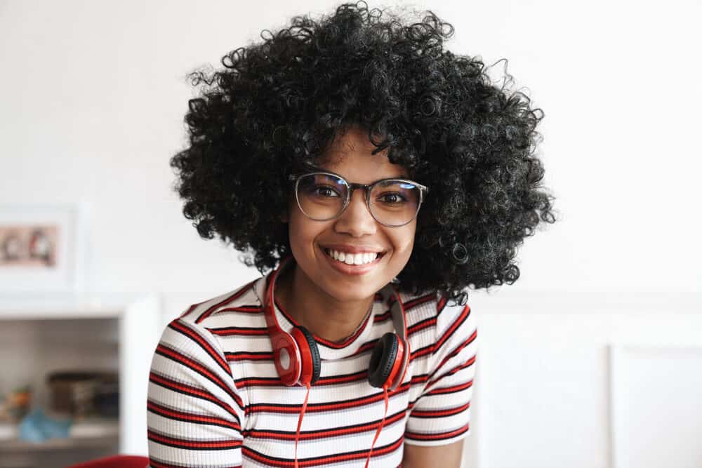 Cute African American hair model with big curls created from jumbo rollers and a hood dryer