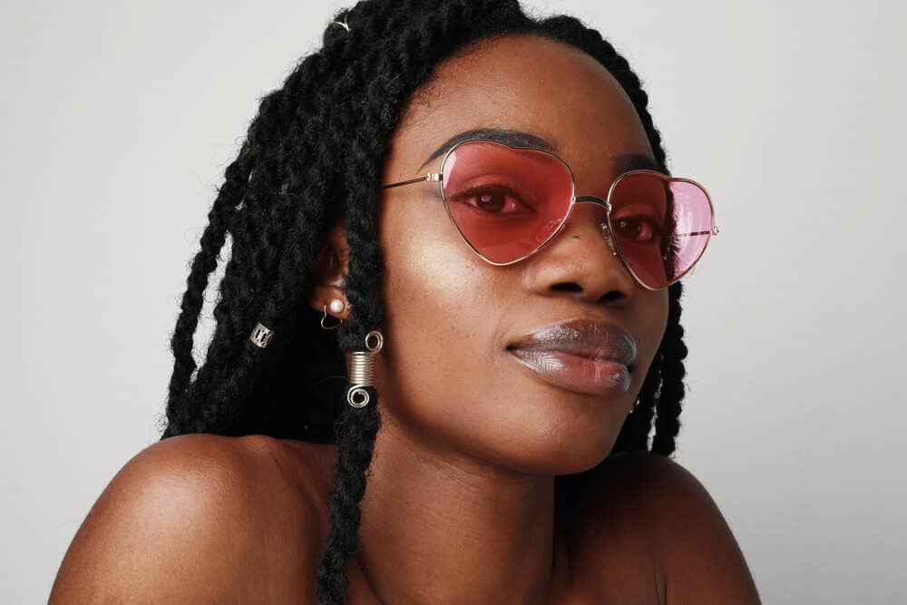 Young black woman with braided synthetic hair wearing pink shades and lip gloss