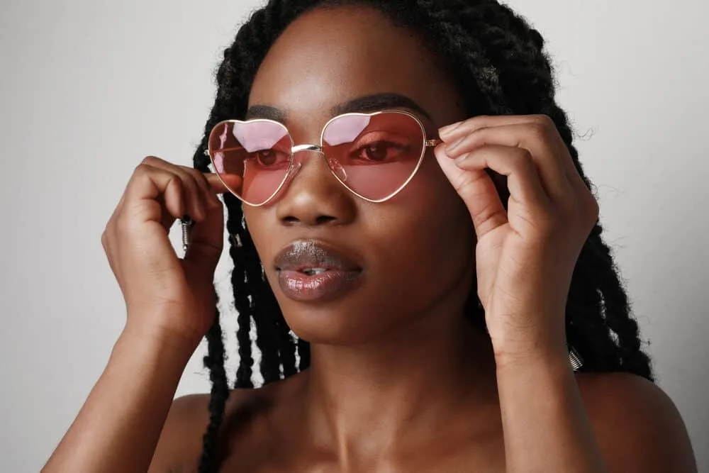 Dark skinned beauty with black hair wearing rose-colored shades to protect her eyes from UV rays