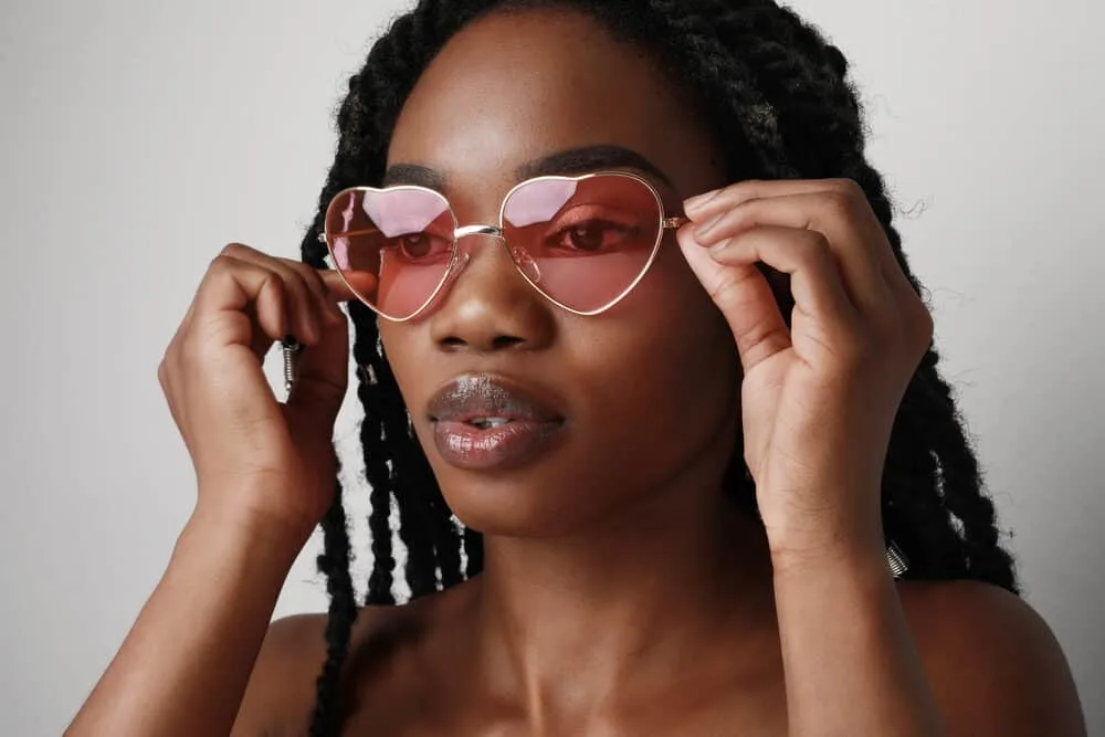Can You Get Braids Wet in the Shower, Pool, or Rain? What Happens? 4 Dark skinned beauty with black hair wearing rose-colored shades to protect her eyes from UV rays