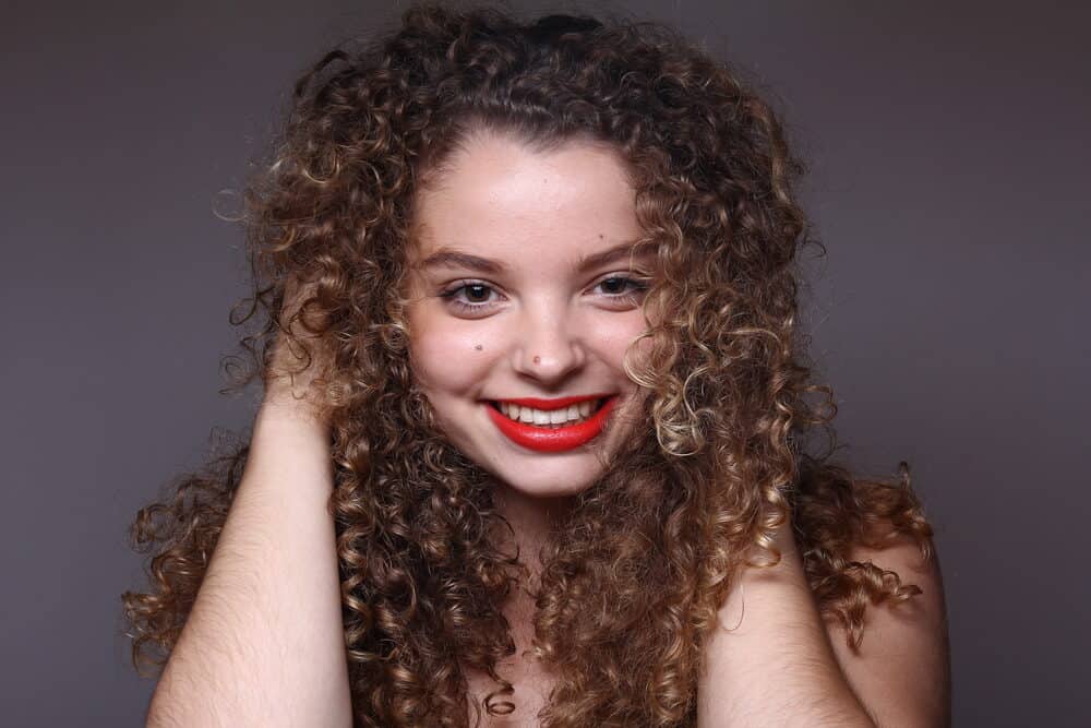 Woman with ombre curls rubbing her hands through her hair