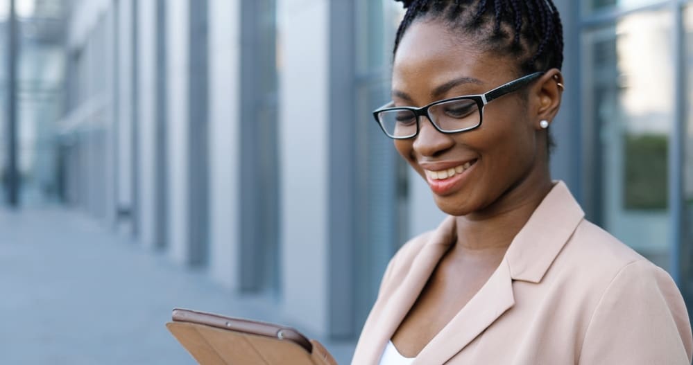 Businesswoman in glasses using an iPad wearing new braids following a session in the salon chair