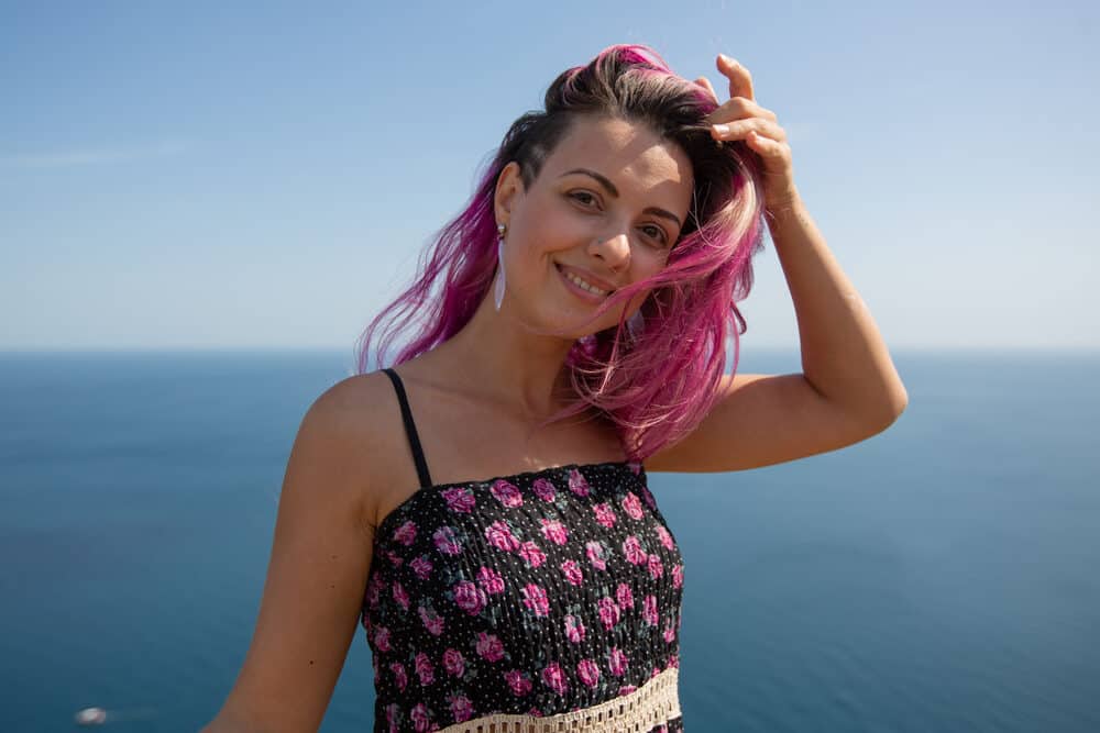 Woman with a brownish rose gold hair color with pink semi-permanent hair dye covering her natural shade