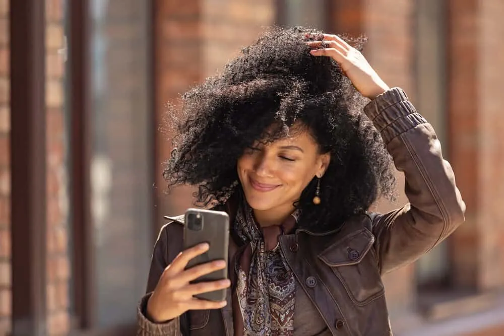 Is Herbal Essences Bad for Your Hair? What About Their Shampoo and Other Products? 6 Black woman rubbing her fingers through her curly hair type washed with Herbal Essences shampoo-brand