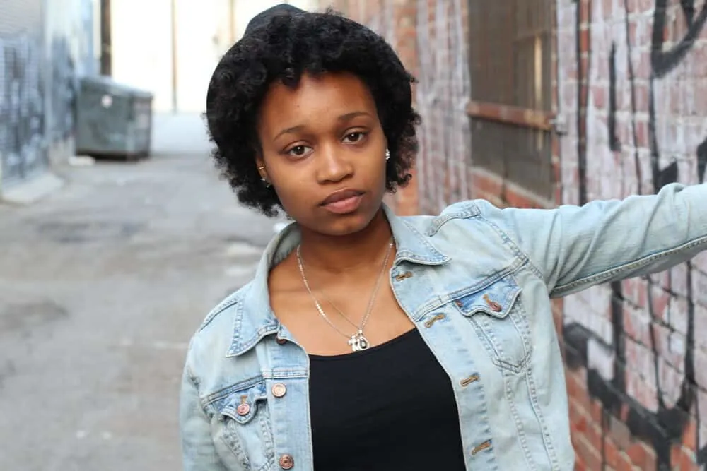 Do Black People Wash Their Hair? How Often Do They Wash? 1 Cute black girl with bouncy curls on fine "afro hair" wearing a blue jean jacket and a black undershirt