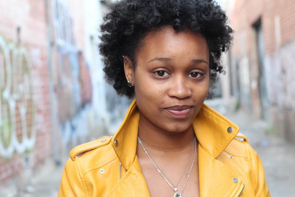 Lady with type 4 African American hair type wearing a yellow jacket and short hair-cut