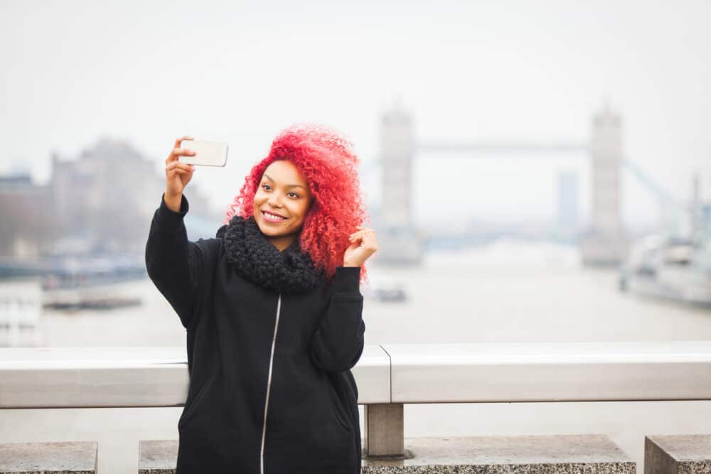 Black female wearing a bright red semi-permanent color with a black winter coat