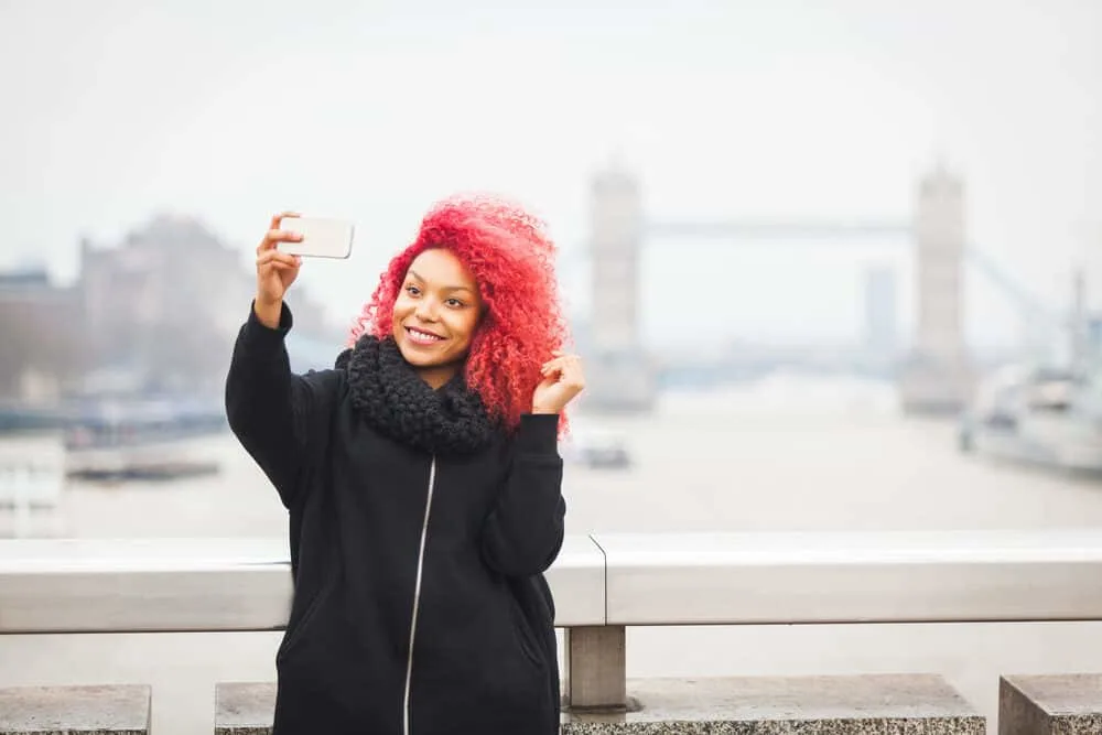How To Get Arctic Fox Out of Hair at Home With 10 Easy Options 5 Black female wearing a bright red semi-permanent color with a black winter coat