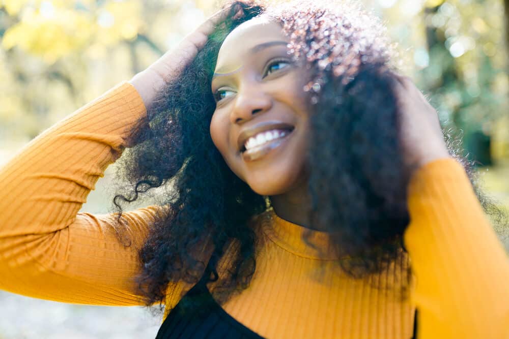 Beautiful young African American lady with thinning hair edges rubbing fingers through her long hair