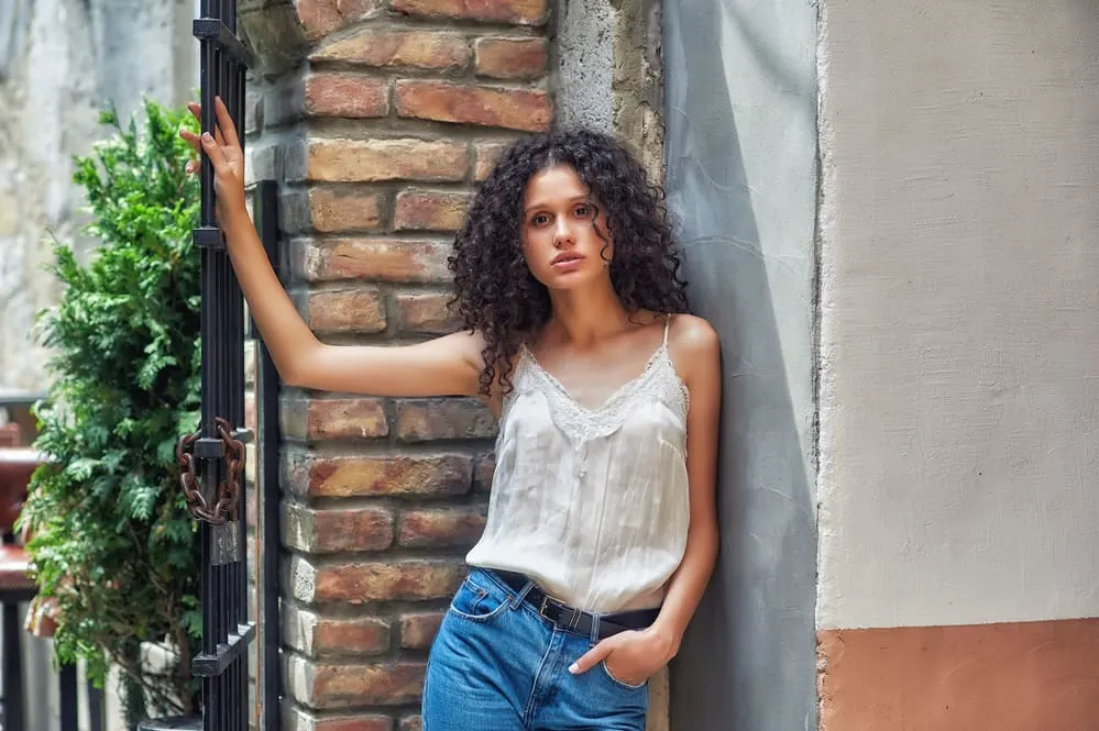 Can a White Person Use a Hair Relaxer? What Happens? What Does It Do? 7 Young lady with brownish-black hair leaving her hair-stylist wearing a white shirt and blue jeans