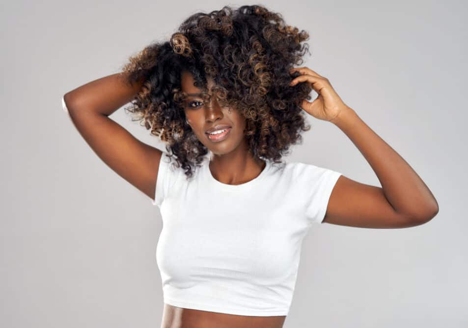 Black woman with curly hair strands styled with curl cream to retain moisture