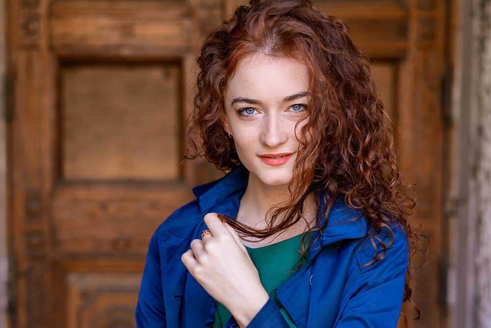 White girl with 3b waves, blue eyes, and red lipstick wearing a green shirt