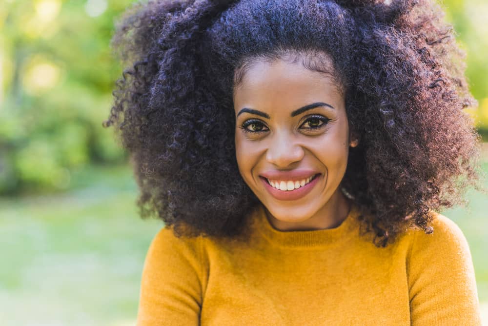 African American female with a kinky hair type styled with pure coconut oil wearing an orange sweater