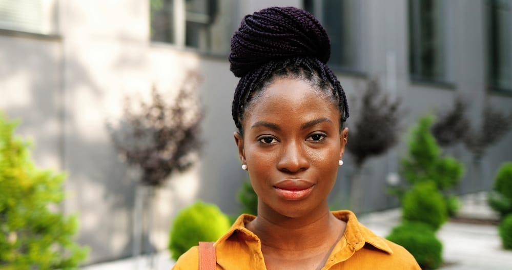 Beautiful African American lady wearing tight box braids recently used hair oil to loosen too-tight braids