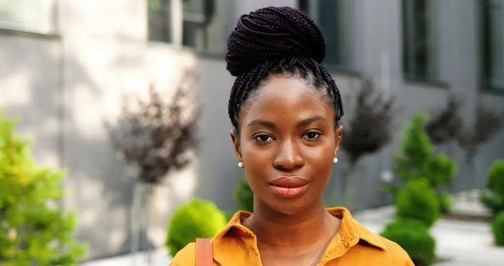 How To Relieve Tight Braids Causing Headaches, Pain, Bumps, and More 1 Beautiful African American lady wearing tight box braids recently used hair oil to loosen too-tight braids