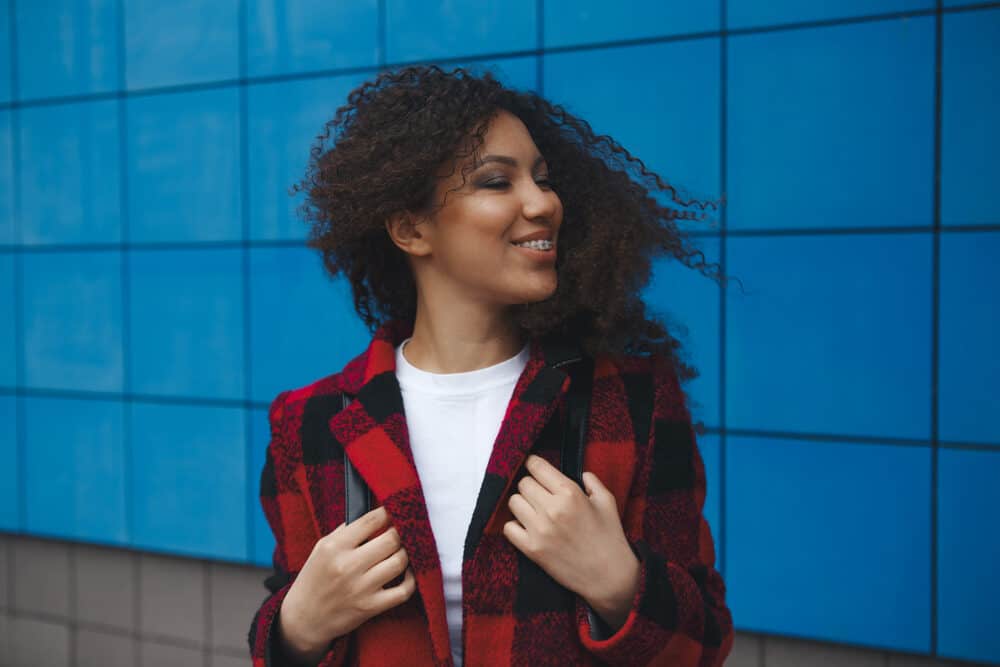 Cute black female with braces, turning her head as the wind blows her type 3a curls.