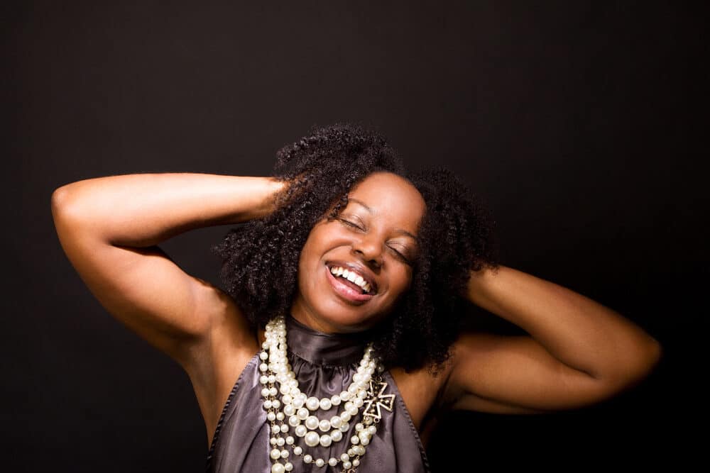 Female celebrating after detangling a massive rats nest with her arms behind her head