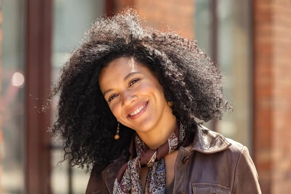 Black girl with naturally curly hair washed with coconut milk shampoo wearing a brown leather jacket