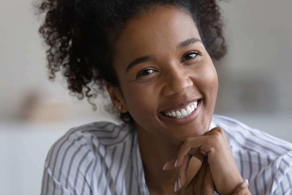 Beautiful young African American woman with healthy hair wearing a blue and white dress shirt