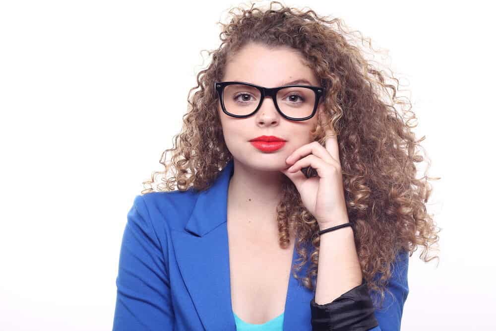 A white person with wavy hair, red lipstick, and black glasses