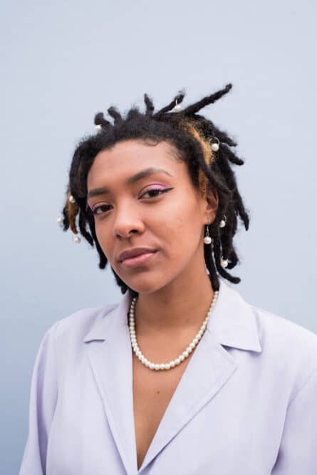Woman with dreadlocks and natural-looking make-up wearing white pearls