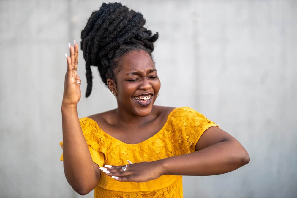 Lady with longer dreads laughing as she does a yoga pose