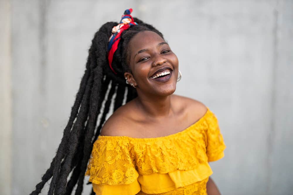 Cute female with long wick locs wearing a yellow dress