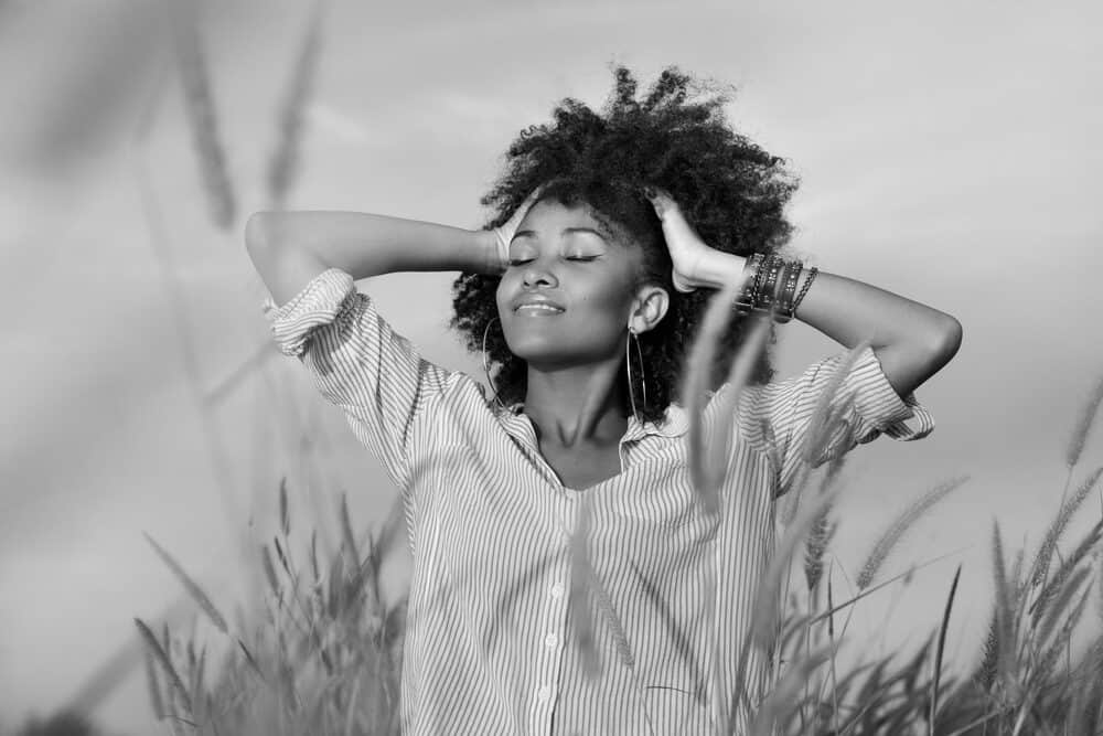 Black girl rubbing her fingers through her bouncy curls styled with eucalyptus oil 