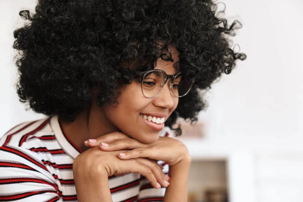 Black girl with 4B curls wearing eye glasses while using a laptop