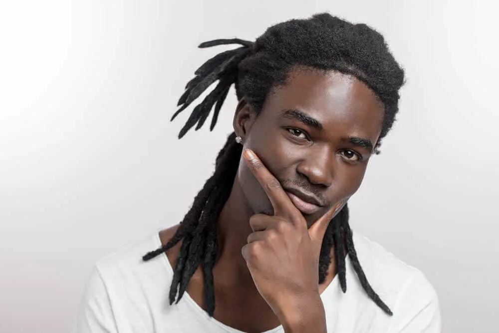 Black man with a black hair color wearing locs started by palm rolling
