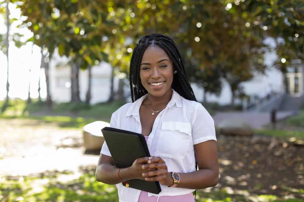 Cute black girl wearing a white dress shirt and a protective hairstyle with a big smile standing near a grocery store