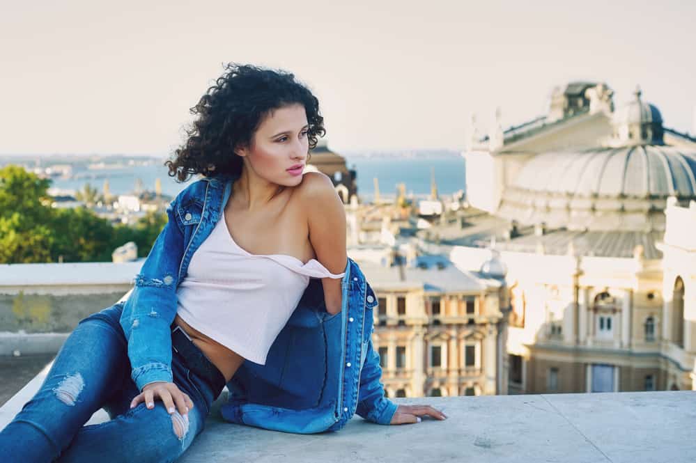 Young woman taking photos on the roof with curly brown hair