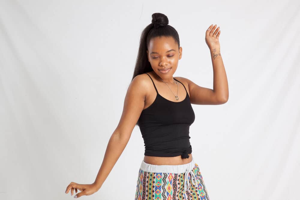 Black girl wearing a black top and African print casual pants with a 4B hair type 