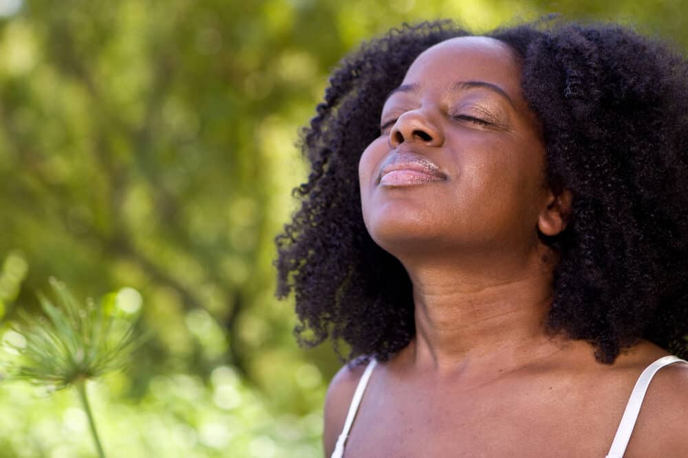 African American female with curly long hair with tiny knots enjoying the fresh air outside